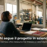 Persona alla scrivania in un ufficio di produzione davanti a un calendario con blocchi di tempo vuoti - referente interno progetto gestionale